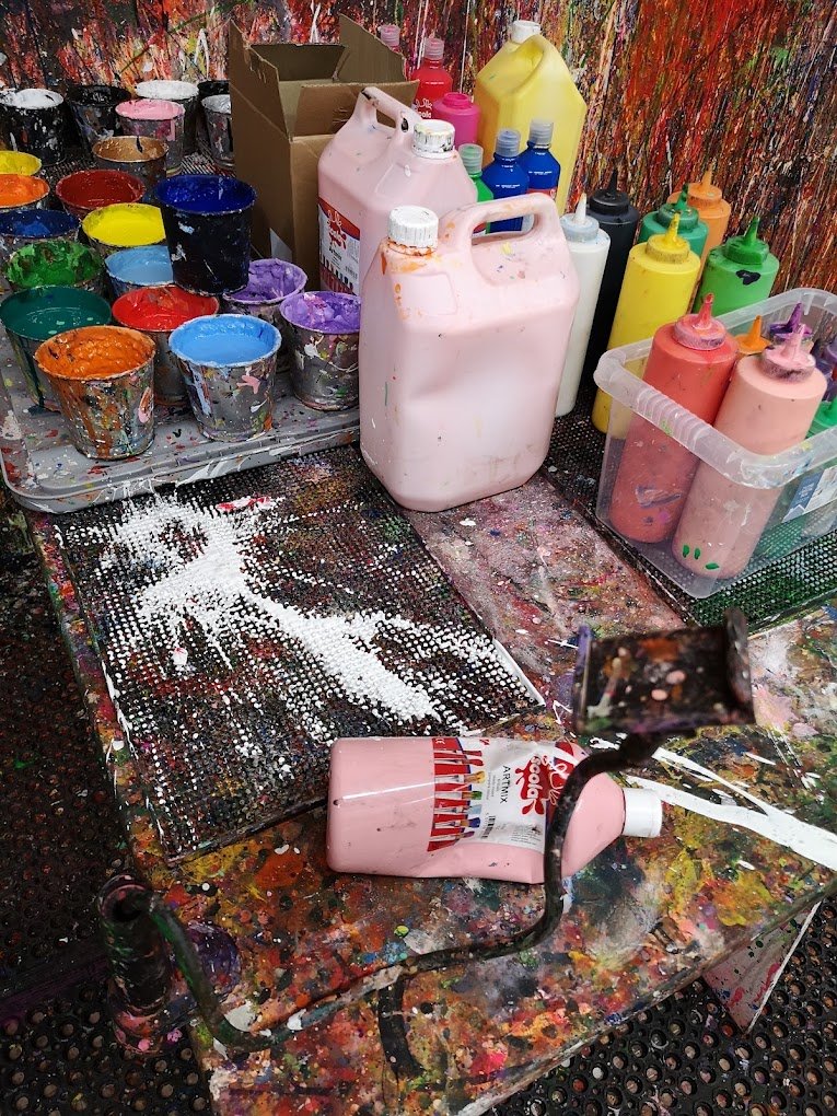 Bulk pink, yellow, and blue paint canisters ready for a messy paint experience Liverpool Day out